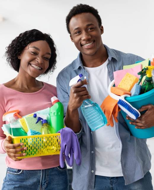 Positive black couple with cleaning tools posing in kitchen, funny african american man and woman standing together with buskets full of cleaning supplies and smiling, house-keeping concept