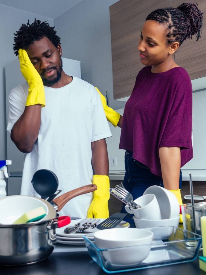 unhappy tired african american couple standing near the table full of dirty plates and cups.